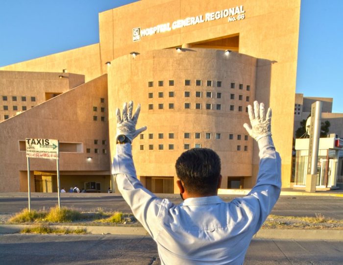 Con sus manos en alto, un hombre realiza una oración frente al Hospital General Regional 66 del IMSS, donde se concentra el mayor número de pacientes con COVID-19 en Ciudad Juárez. 