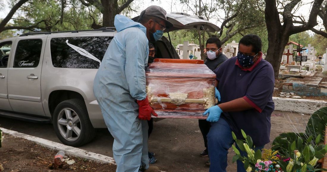 Trabajadores del Panteón San Lorenzo Tezonco y funeraria cargan el féretro de una muerte a causa de COVID-19.