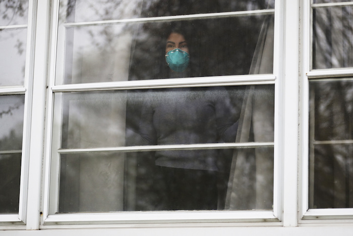 Francy Sandoval, recepcionista en una clínica comunitaria, observa desde una ventana de su casa en Melrose Park, Illinois, el jueves 23 de abril de 2020.