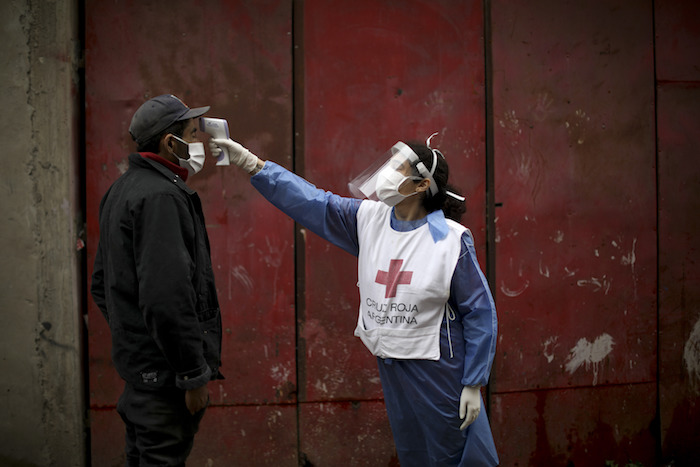 Una voluntaria de la Cruz Roja mide la temperatura de un residente dentro del barrio marginal de Fraga durante un confinamiento ordenado por el Gobierno para frenar la propagación del nuevo coronavirus, en Buenos Aires, Argentina, el sábado 6 de junio de 2020. 