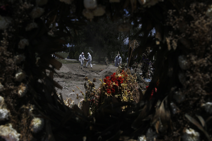 Empleados de cementerio en equipo protector entierran a víctimas de COVID-19 en el Panteón de San Lorenzo Tezonco en una sección reservada para personas que murieron del nuevo coronavirus en la Alcaldía Iztapalapa en Ciudad de México, el lunes 2 de junio de 2020. Los empleados cargan los ataúdes solos, un trabajo que en el pasado pudieron haber realizado los dolientes. 