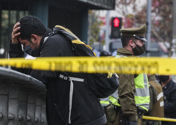 Un migrante peruano es detenido por aparecer en una base de datos policiales como positivo para COVID-19, en el centro de Santiago, Chile, el lunes 8 de junio de 2020. La policía ha rodeado el área alrededor del hombre con cinta policial para evitar que las personas entren en contacto con él. 