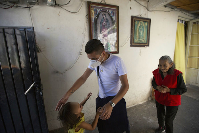 El doctor Juan Antonio Salas, en el centro, bromea con la nieta de su paciente Cleotilde Borja, una sobreviviente de COVID-19, justo al final de su visita médica voluntaria a su hogar en la Ciudad de México, el viernes 5 de junio de 2020. 