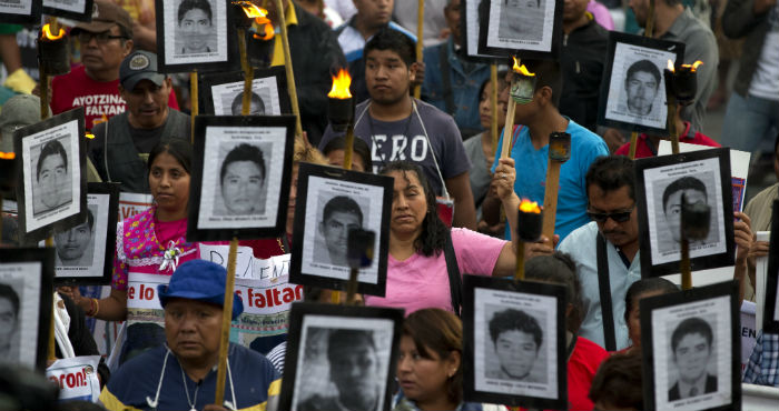 En esta foto del 26 de abril de 2016, familiares y activistas de 43 estudiantes normalistas desaparecidos en el estado de Guerrero portan sus retratos para exigir que no se cierre el caso en Ciudad de México.