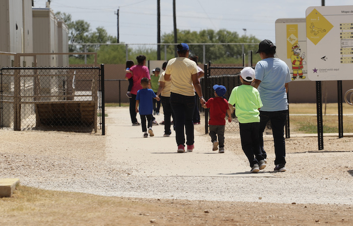 En esta fotografía del 23 de agosto de 2019, unos migrantes se toman de las manos mientras salen de una cafetería en un centro de detención del Servicio de Control de Inmigración y Aduanas de Estados Unidos en Dilley, Texas. 