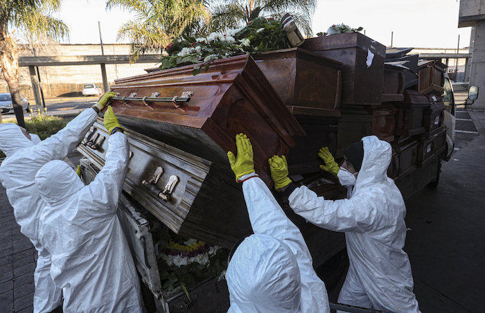 Operarios recuperan y apilan los féretros de personas incineradas durante la pandemia del coronavirus, en el cementerio de La Recoleta, en Santiago, Chile, el 30 de junio de 2020. Los ataúdes son recopilados y destruidos por una empresa especializada en basura orgánica. 