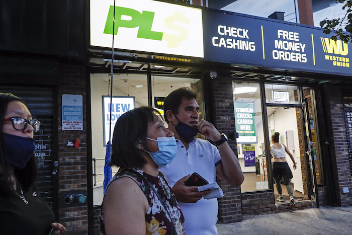 Magnolia Ortega centro En El Exterior De Una Oficina De Western Union Con Su Esposo Arturo Morales Y Su Hija Marlene Tras Enviar Dinero a Su Familia En México El De Junio De En Staten Island Nueva York Ortega Perdió Su Empleo Limpiando Casas Por La Pandemia Del Coronavirus Lo Que Redujo La Cantidad De Dinero Que Envía Cada Mes a Su Casa Está Considerando Regresar a Su Pueblo Natal San Jerónimo Xayacatlán Pero Dice Que Allí Tampoco Hay Trabajo Y Eso Significaría Que Un Miembro Menos De La Familia Envía Remesas