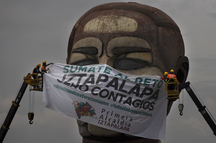 Trabajadores de la ciudad colocan una mascarilla gigante con un texto escrito en español que dice "Súmate al reto, Iztapalapa cero contagios", en el museo Cabeza de Juárez en medio de la pandemia de COVID-19, en Iztapalapa, Ciudad de México, el miércoles 12 de agosto de 2020. 