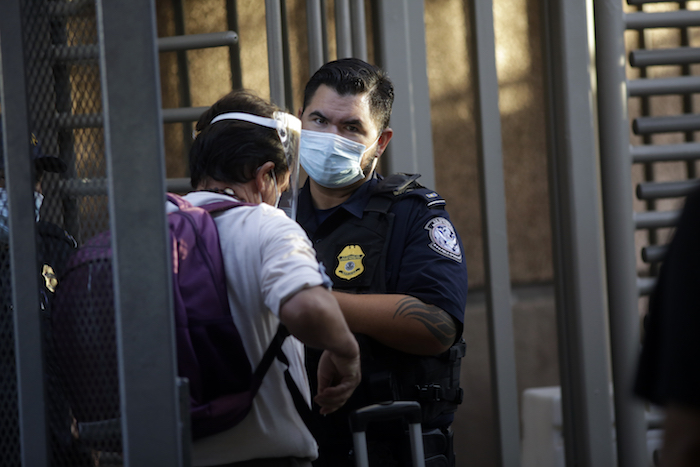 Un agente de la Oficina de Aduanas y Protección Fronteriza de Estados Unidos habla con unas personas mientras cruzan la frontera desde Mexicali, México, hacia Calexico, California, el miércoles 22 de julio de 2020. 