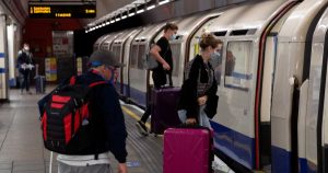 Personas con mascarillas que aterrizaron en el aeropuerto de Heathrow suben a un tren subterráneo con destino a Londres, en las terminales del metro Heathrow 2 y 3 en Londres.