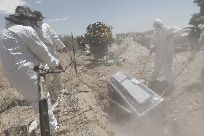 Unos trabajadores portan equipo de protección mientras entierran el martes 19 de mayo de 2020 un ataúd en una zona del cementerio municipal de San Rafael, destinada para los casos de COVID-19 en Ciudad Juárez, México. 