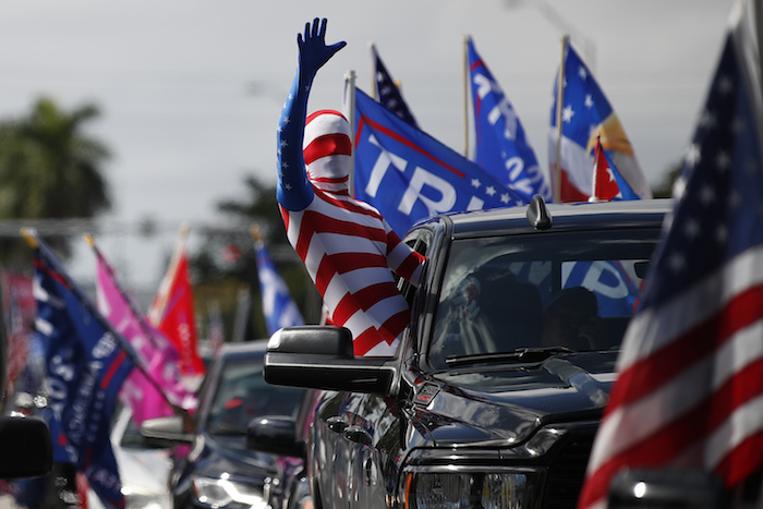 Un hombre vestido con un traje de la bandera estadounidense saluda el domingo 1 de noviembre de 2020 antes de que arranque una caravana de vehículos en el Tropical Park en apoyo al Presidente Donald Trump, en Miami.