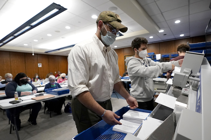 Trabajadores electorales colocan los sobres de votos por correo en una máquina antes de que sean contabilizados en Harrisburg, Pensilvania. 