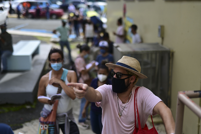 Votantes, con mascarilla por la pandemia del coronavirus, esperan en fila para depositar sus boletas en las elecciones generales, en un centro de votación habilitado en la escuela Rafael Labra, en San Juan, Puerto Rico, el 3 de noviembre de 2020. 