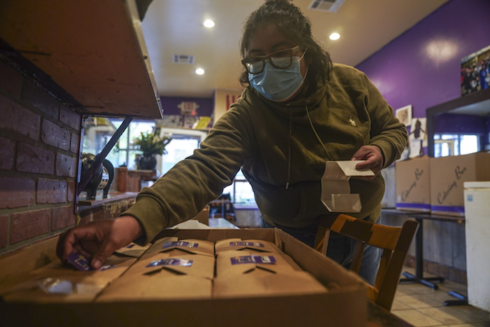 Yajaira Saavedra coloca calcomanías que dicen "La Morada Bx Mutual Aid Kitchen" en cajas de comida en su restaurante que se están preparando para distribuir en su vecindario del sur del Bronx, el miércoles 28 de octubre de 2020, en Nueva York. 