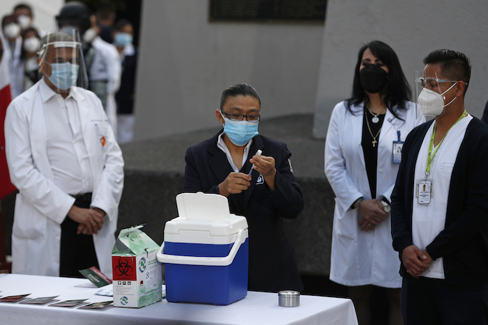 Una trabajador de la salud sostiene un frasco de la vacuna contra COVID-19 mientras se inyectan las primeras dosis a los trabajadores de la salud en el Hospital General de la Ciudad de México, el jueves 24 de diciembre de 2020 en la madrugada. Los primeros lotes de vacunas producidas por Pfizer y su socio alemán, BioNTech llegaron el día anterior. 