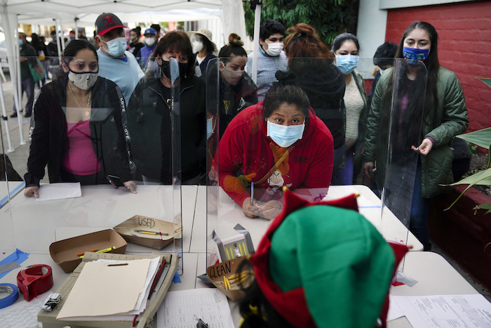 Fotografía de archivo del 17 de diciembre de 2020, de personas registrándose para recibir alimentos en Los Angeles Boys & Girls Club en el barrio Lincoln Heights de Los Ángeles, California. 