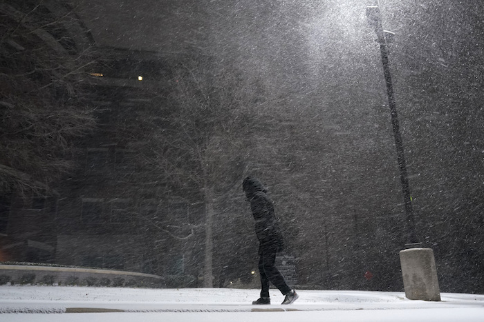 Una mujer camina bajo una nevada en San Antonio, el domingo 14 de febrero de 2021.