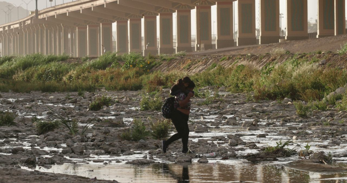 Mujer migrante cruza entre tormenta de arena el Río Bravo la frontera en Juárez.