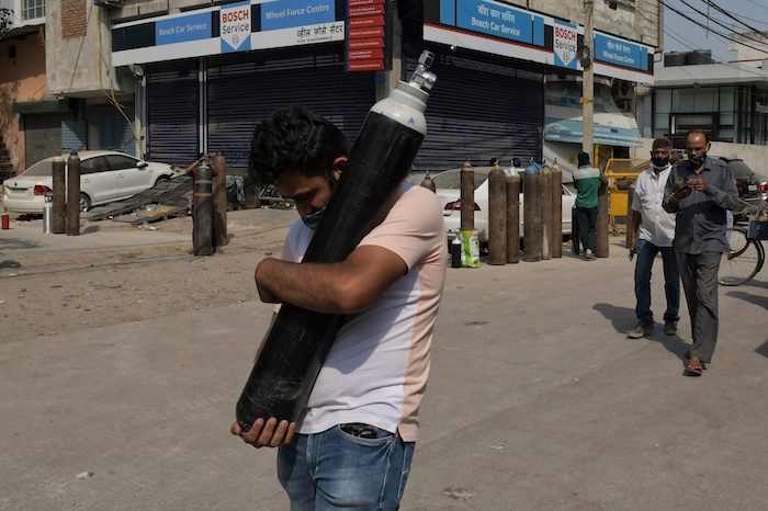 En Esta Imagen De Archivo Del De Mayo De Un Hombre Camina Con Una Botella Llena De Oxígeno Mientras Varios Familiares De Pacientes De Covid Esperan En Fila Para Rellenar Sus Botellas En La Zona De Mayapuri En Nueva Delhi India