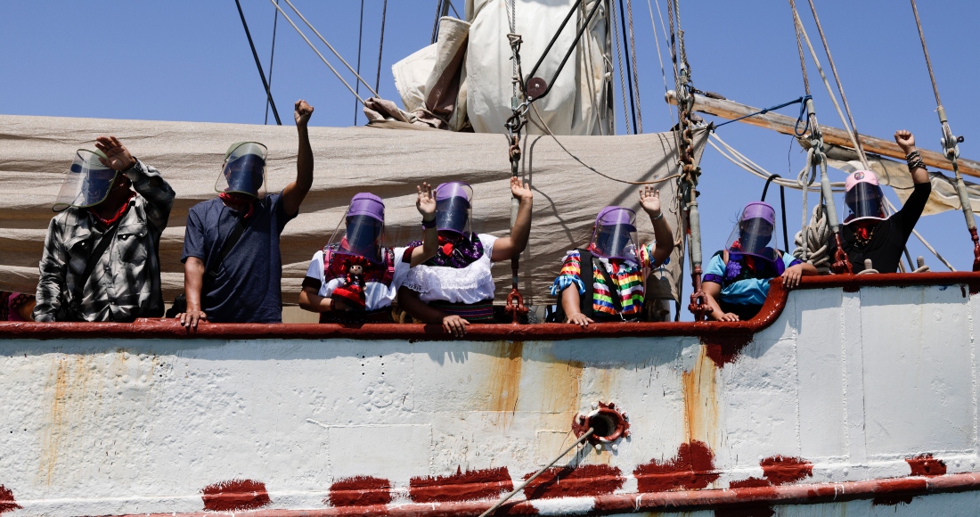 En esta foto del 30 de abril del 2021, una delegación del Ejército Zapatista de Liberación Nacional saluda desde el barco que les llevará a Europa en ocasión del 500mo aniversario de la Conquista de México, desde Isla de Mujeres, en el estado de Quintana Roo.