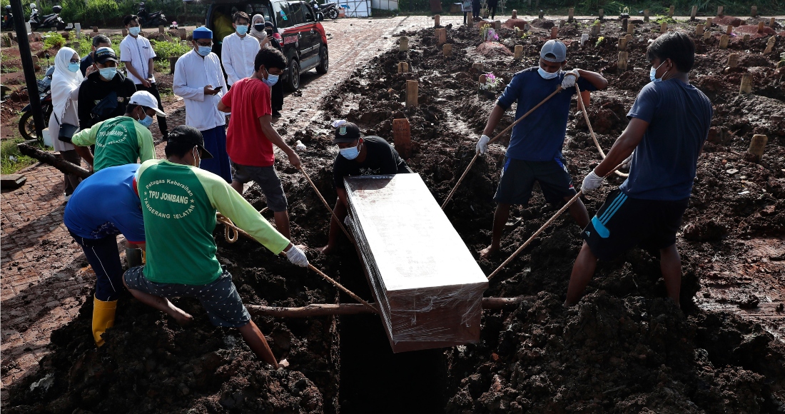 Unos trabajadores bajan un ataúd durante la inhumación de una víctima fatal de COVID-19, en una zona especial para esos cadáveres en el cementerio público de Jombang, el lunes 21 de junio de 2021 en Tangerang, en las afueras de Yakarta, Indonesia.