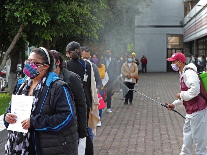 Grupos de personas hacen fila mientras son desinfectados en un modulo de pruebas para detectar la COVID-19, el 15 de julio de 2021, en la Ciudad de México (México).