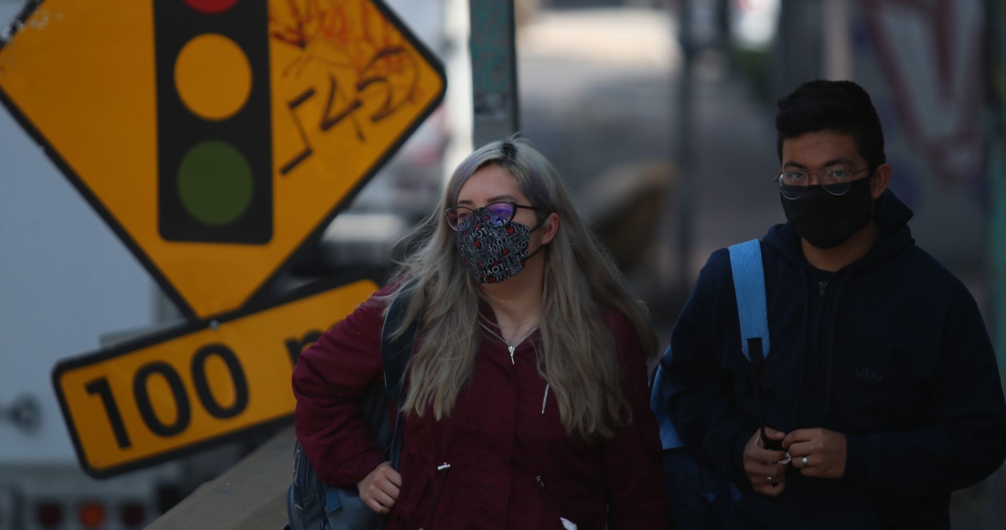 Jóvenes caminan sobre avenida Constituyentes, en la Ciudad de México, portando cubrebocas personalizados.