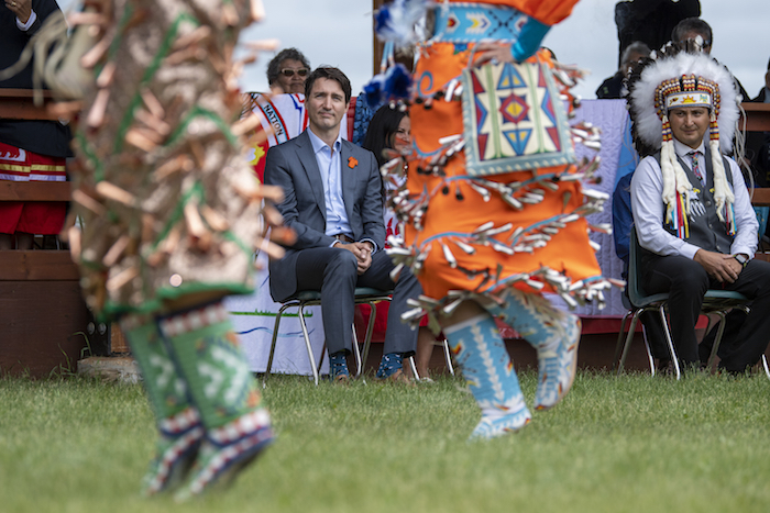 El Primer Ministro Justin Trudeau y el jefe Cadmus Delorme ven a danzantes durante la celebración de la aprobación de una transferencia de control de niños a cargo de la comunidad en la nación indígena Cowessess, Saskatchewan, el martes 6 de julio de 2021.