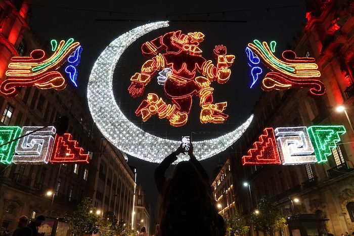 Asistentes toman fotos a la luminaria con motivo de los "500 años de Resistencia Indígena".