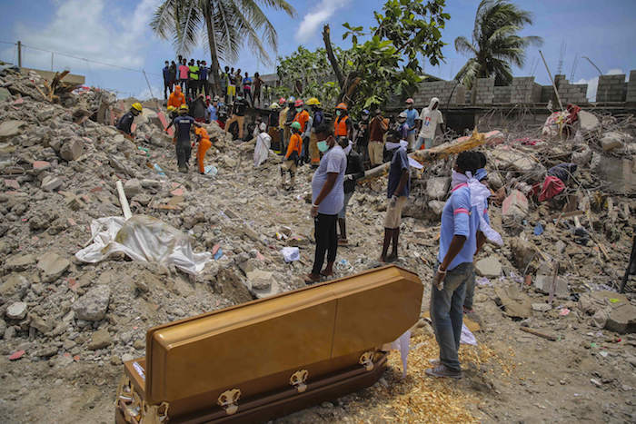 Decenas de personas permanecen de pie el miércoles 18 de agosto de 2021 , en Les Cayes, Haití, junto a un ataúd con los restos de François Elmay, cuyo cadáver fue recuperado entre los escombros de una casa destruida por un terremoto de 7.2 grados.