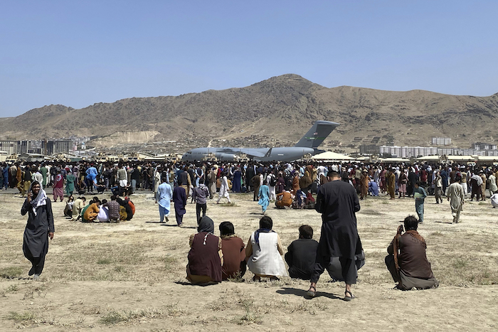 Cientos de personas esperan junto a un avión de transporte C-17 de la Fuerza Aérea de Estados Unidos en el perímetro del aeropuerto internacional de Kabul, Afganistán, el 16 de agosto de 2021.