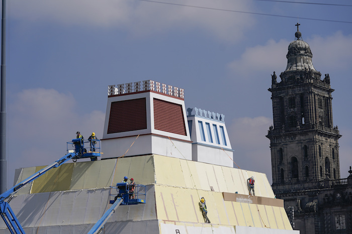 Operarios construyen una réplica del Templo Mayor azteca, con una imagen del dios precolombino Quetzalcoatl adornando los edificios colindantes, en la Plaza del Zócalo, en Ciudad de México, el 9 de agosto de 2021.