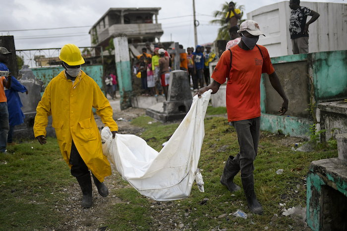 Dos hombres cargan con el cuerpo de un niño, hallado entre los escombros de un edificio derruido, hasta el cementerio de Les Cayes, Haitó, el 17 de agosto de 2021, tres días después de un sismo de magnitud 7.2 que remeció la parte suroccidental del país.