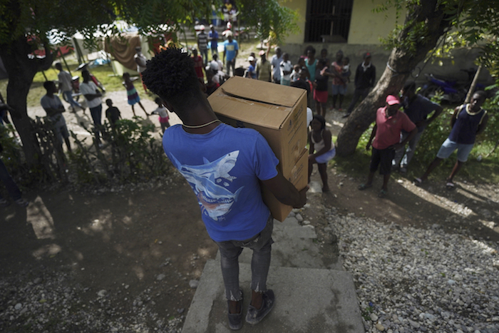 Un hombre carga dos cajas que contienen alimentos el miércoles 18 de agosto de 2021, en Les Cayes, Haití, las cuales fueron enviadas por el Gobierno de la ciudad para los residentes que se quedaron sin hogar luego del sismo de magnitud de 7.2 que sacudió la nación.