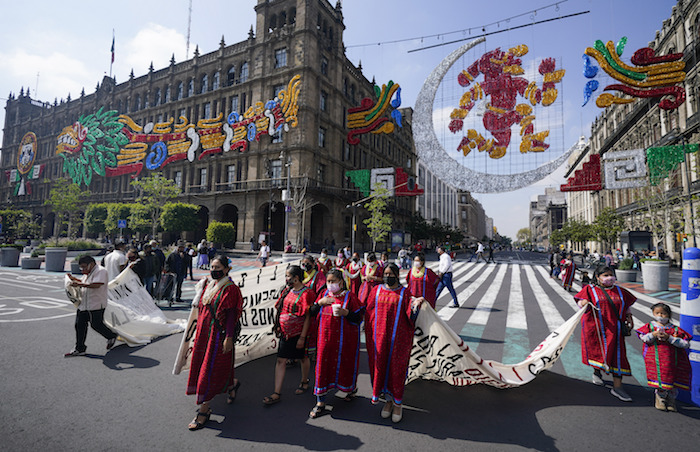 Indígenas triquis, originarios del estado de Oaxaca pero que viven en la Ciudad de México, protestan bajo una imagen de la diosa precolombina de la luna, Coyolxauhqui, para que se les permita vender sus productos cerca de la principal plaza de la capital, el Zócalo, el 9 de agosto de 2021.