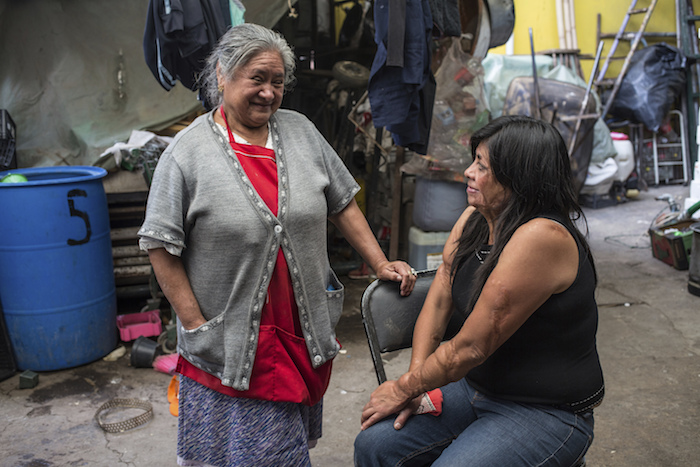 Elisa Xolalpa, quien sobrevivió a un ataque con ácido por su expareja hace 20 años cuando ella tenía 18 años, habla con su mamá Carmen Martínez en el patio de la casa de sus padres en Ciudad de México, el sábado 12 de junio de 2021.