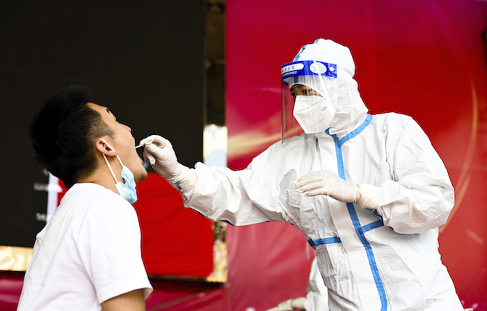 En esta imagen del 5 de julio de 2021 publicada por la Agencia de Noticias XInhua, un trabajador sanitario toma una muestra para una prueba diagnóstica en la ciudad de Ruili, en la provincia suroeste de Yunnan. 