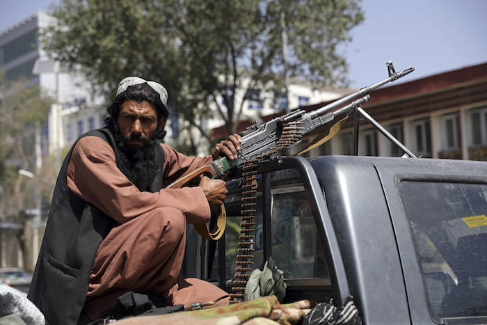 Un combatiente del Talibán apostado con una ametralladora frente al principal ingreso al palacio presidencial en Kabul (Afganistán).