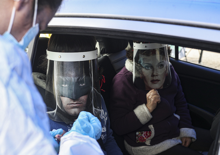 Un Trabajador De La Salud Realiza Una Prueba Rápida De Covid a Ignacio Poblete Con Un Protector Facial Con La Imagen De Batman Acompañado De Su Madre Marisol Aro Usando Un Protector Facial Con La Imagen De La Mujer Maravilla En Santiago Chile El Sábado De Junio De