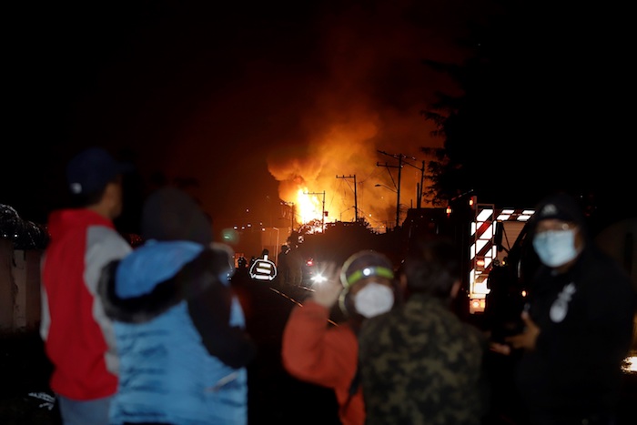 Personas observan el área donde se registró una explosión e incendio, la madrugada de este domingo, en San Pablo Xochimehuacán, en el estado de Puebla (México).