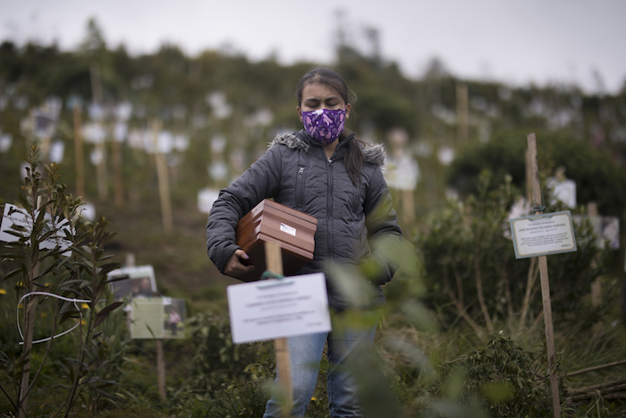 Un familiar porta una urna con los restos cremados de Alejandro Arenas, quien falleció por complicaciones relacionadas con la COVID-19, para ser esparcidos en un cerro en la Reserva Natural El Pajonal de Cogua, al norte de Bogotá, Colombia, 24 de junio de 2021.