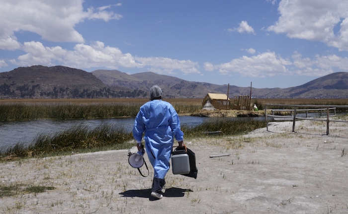 Un trabajador de la salud lleva una hielera llena con dosis de la vacuna de Pfizer contra la COVID-19 durante una campaña de vacunación puerta a puerta dirigida a los residentes del lago Titicaca en Puno, Perú, el miércoles 27 de octubre de 2021.