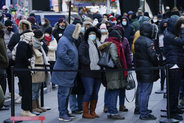 Varias personas esperan en una fila para realizarse a una prueba de COVID-19 en Times Square, Nueva York, el lunes 20 de diciembre de 2021.