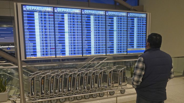 Un hombre observa las pantallas de salidas de vuelos en el Aeropuerto Internacional de Salt Lake City, el viernes 24 de diciembre de 2021.