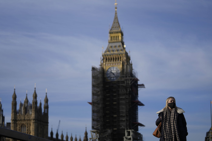 Una mujer usa una mascarilla mientras cruza el puente de Westminster en Londres, el jueves 9 de diciembre de 2021.