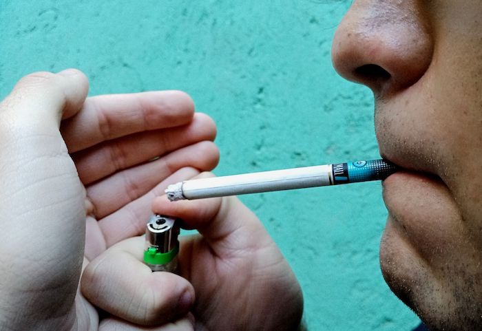 Una persona enciende un cigarro.