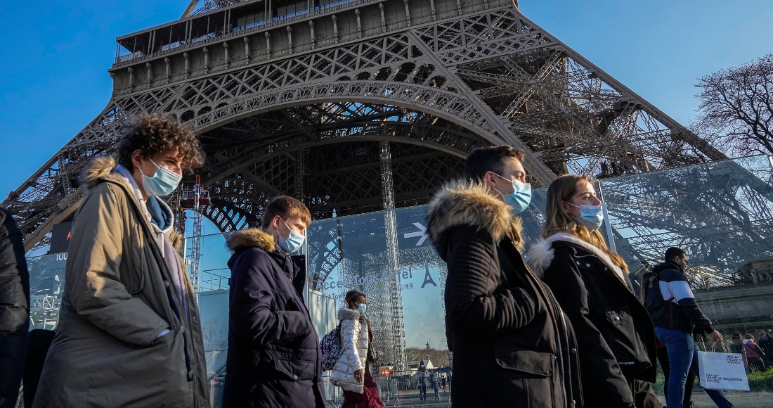 Personas con mascarillas para protegerse de la COVID-19 caminan frente a la Torre Eiffel, el martes 21 de diciembre de 2021, en París.