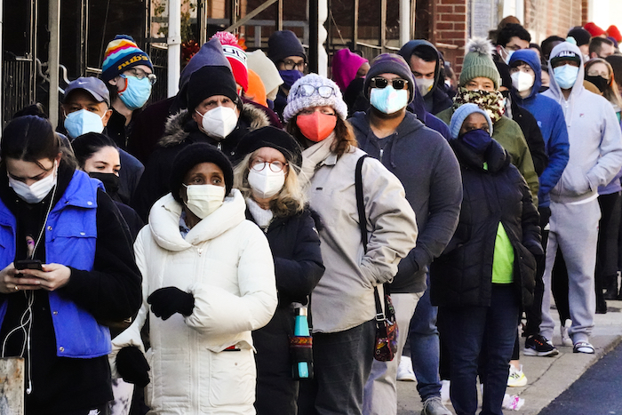 Decenas de residentes de la ciudad hacen una fila que se extiende alrededor de la cuadra para recibir kits gratuitos de prueba rápida de COVID-19 en el hogar, el lunes 20 de diciembre de 2021 en Filadelfia.