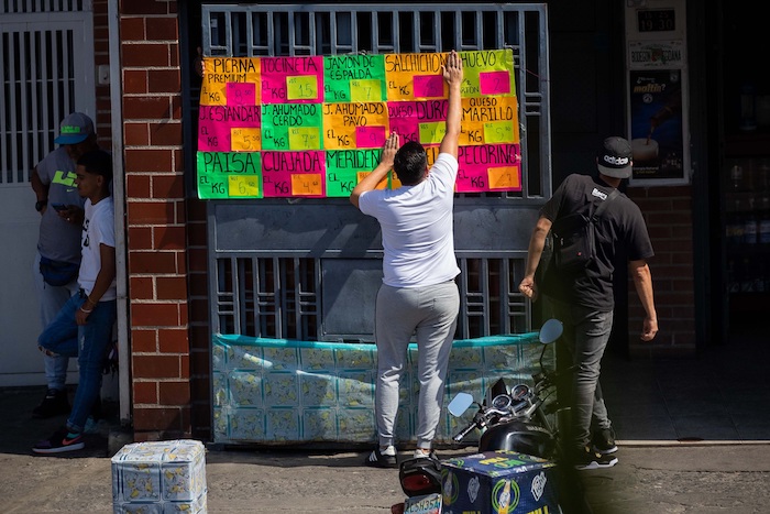 Un hombre ajusta la lista de precios de una tienda de comida, el 18 de enero de 2022, en Caracas (Venezuela).